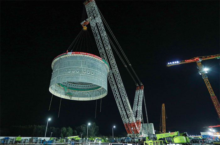 The hoisting of the upper cylinder of the steel containment of the world's first reactor 